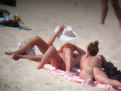Nude sun tanning girls expose themselves to a beach spy cam